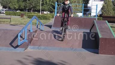 一个男孩正在阳光明媚的<strong>日</strong>子里在滑板公园骑自行车。 <strong>超级</strong>慢动作